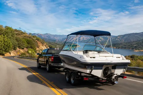 Boat on a trailer being towed down a California highway toward a lake for a weekend trip
